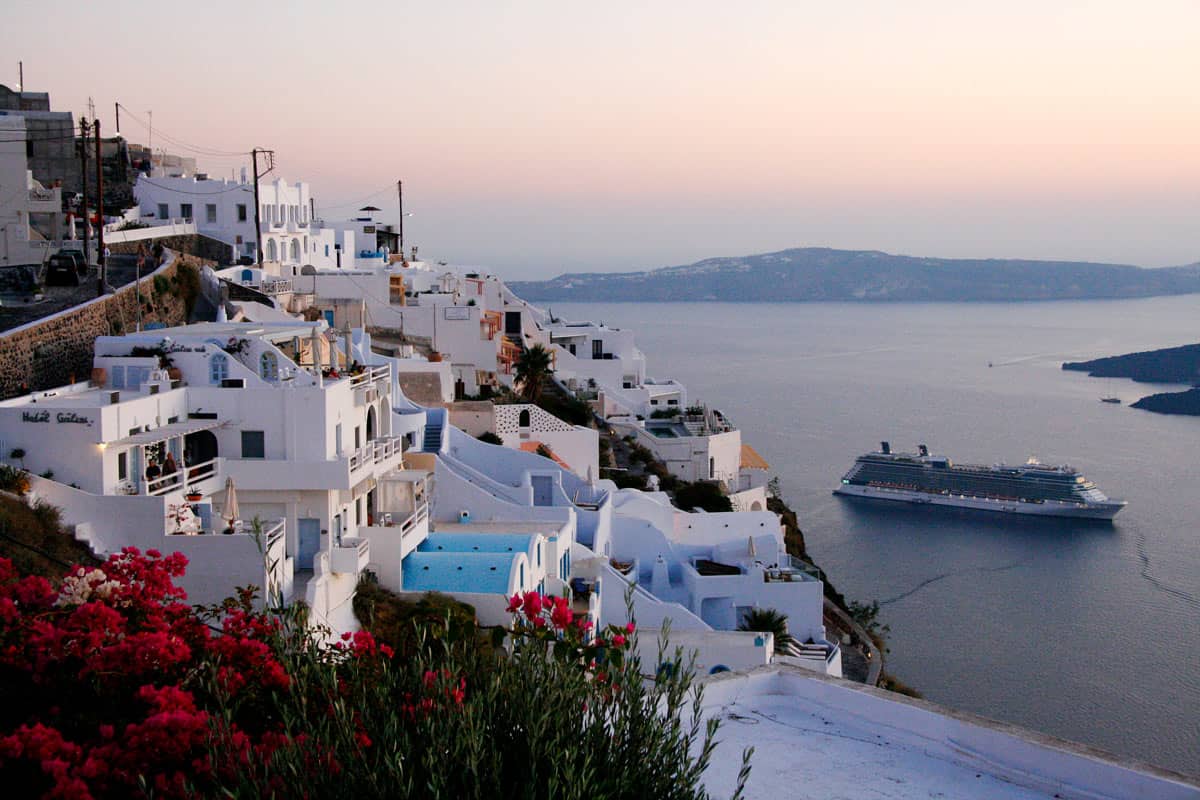 A cruise ship leaves Santorini at sunset