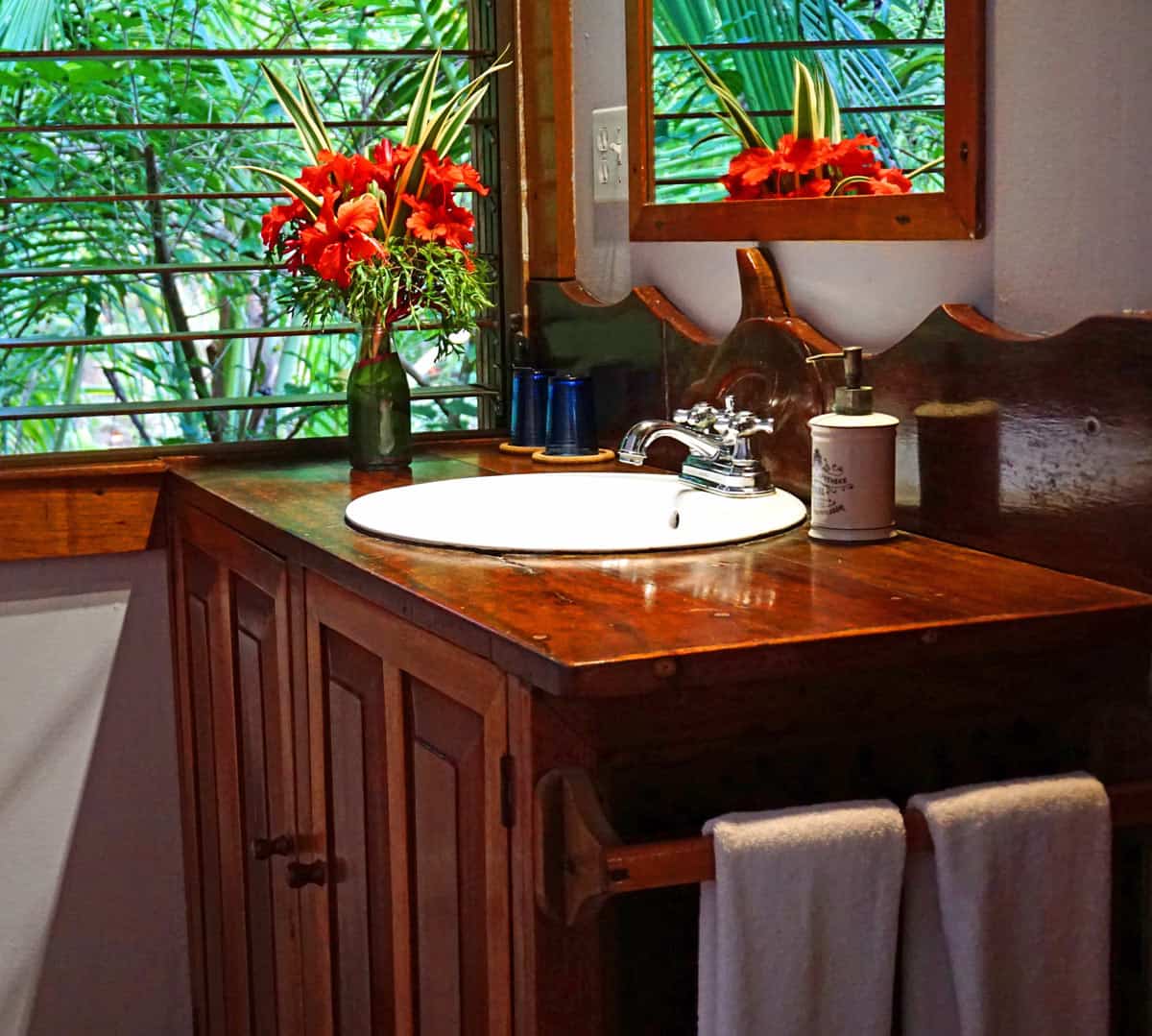 Vase of red flowers on the wooden sink in our Casa Cayuco bathroom