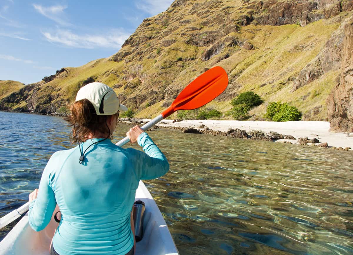 woman in aqua snorkel skin sea kayaking in Indonesia