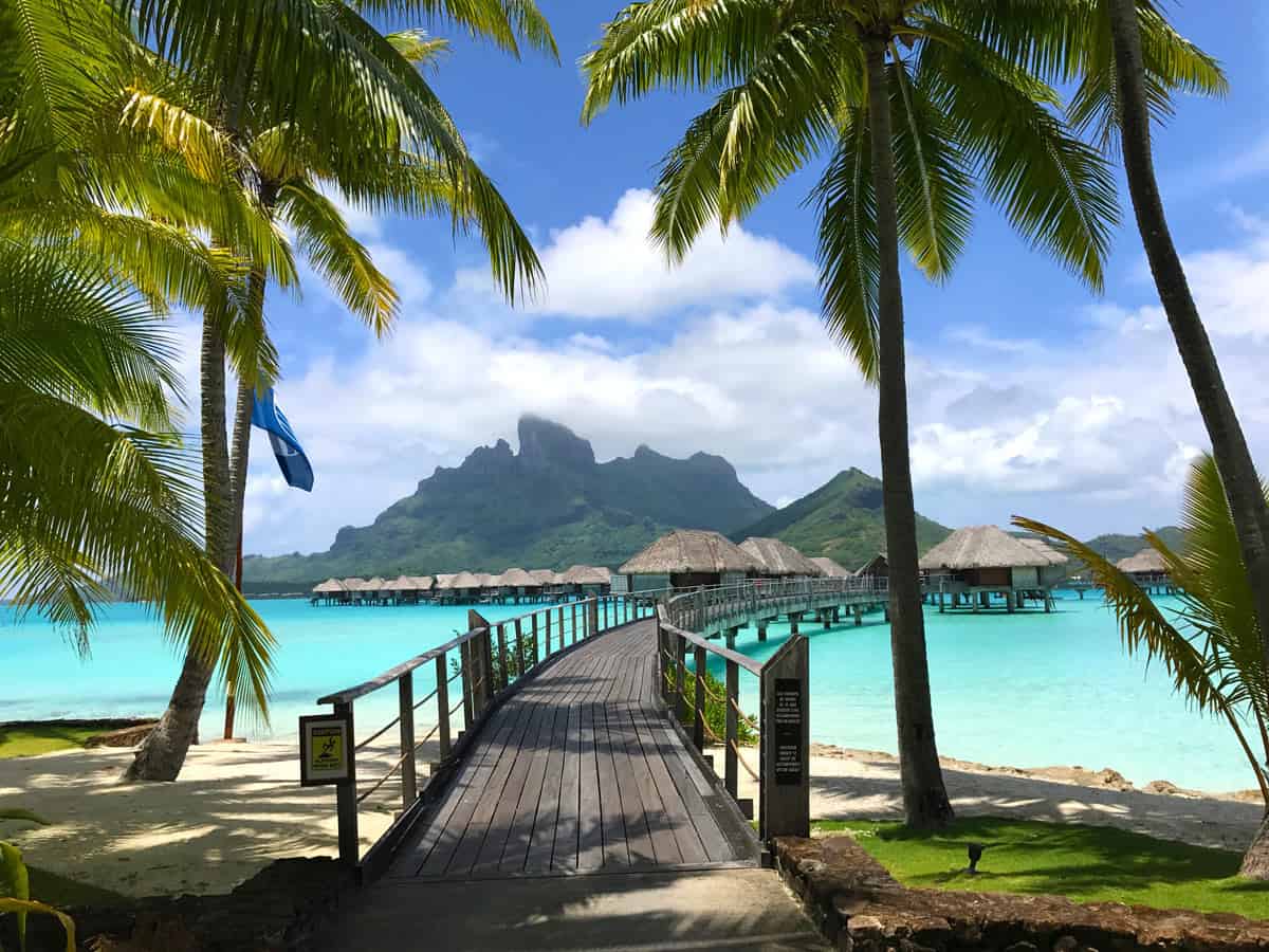 Green jagged peaks of Mount Otemanu rising up behind overwater bungalows of Four Seasons Bora Bora