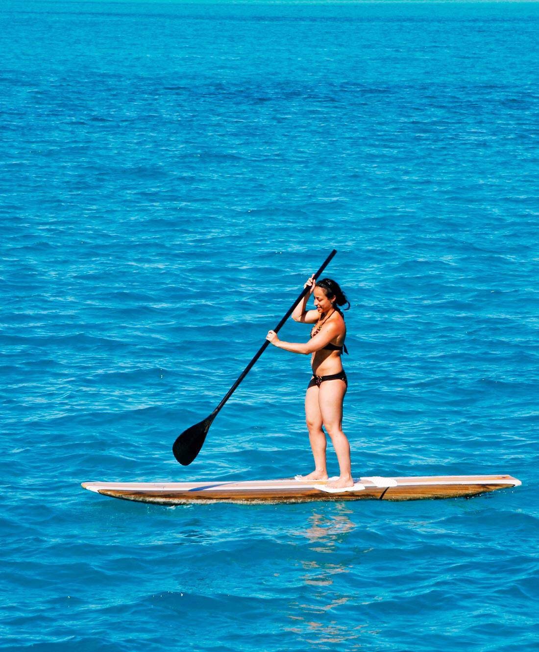 Woman paddleboarding in Bora Bora's turquoise lagoon