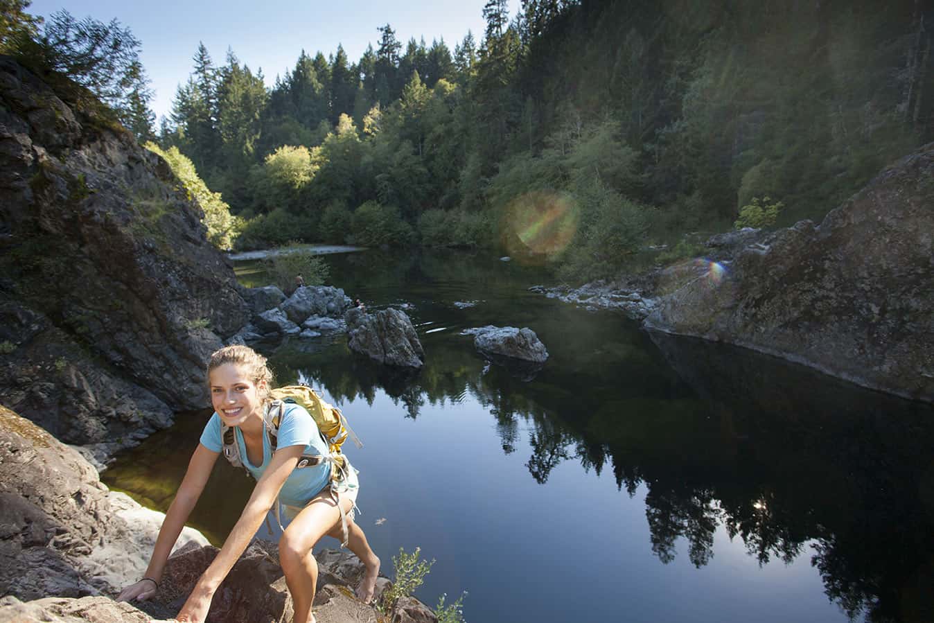Young woman climbs up the cliffs at Sooke Potholes