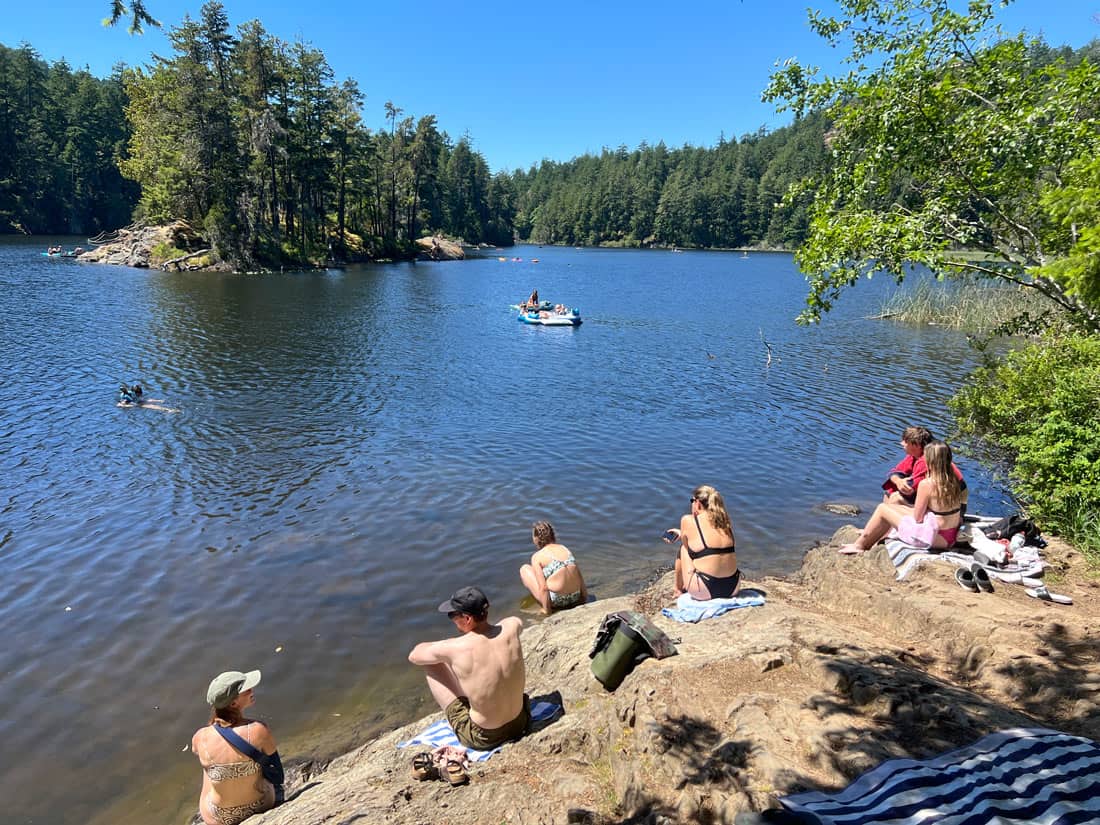 People soaking up the sun on the rocks at Matheson Lake near Victoria, BC
