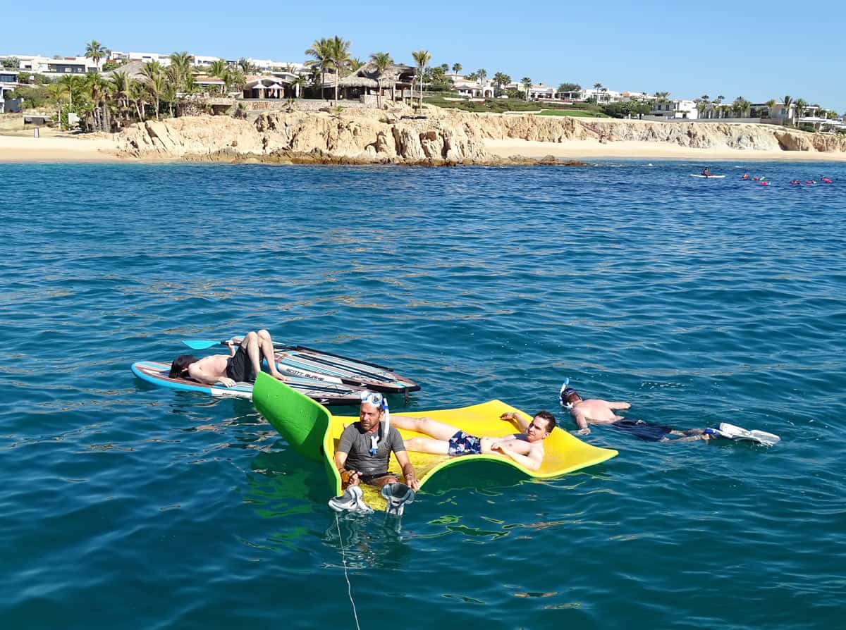 People snorkeling and lying on floating mats in Chileno Bay