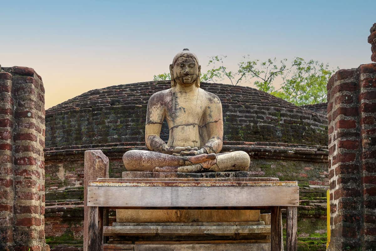 An ancient seated stone Buddha keeps watch among the ruins of Polonnaruwa.