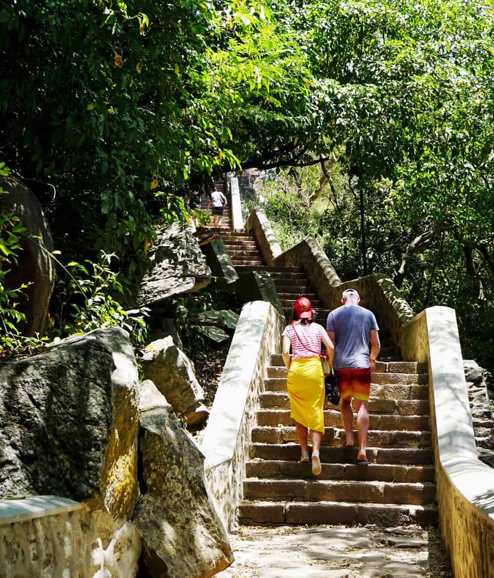 A couple climb up steps to the Dambulla Cave Temple complex