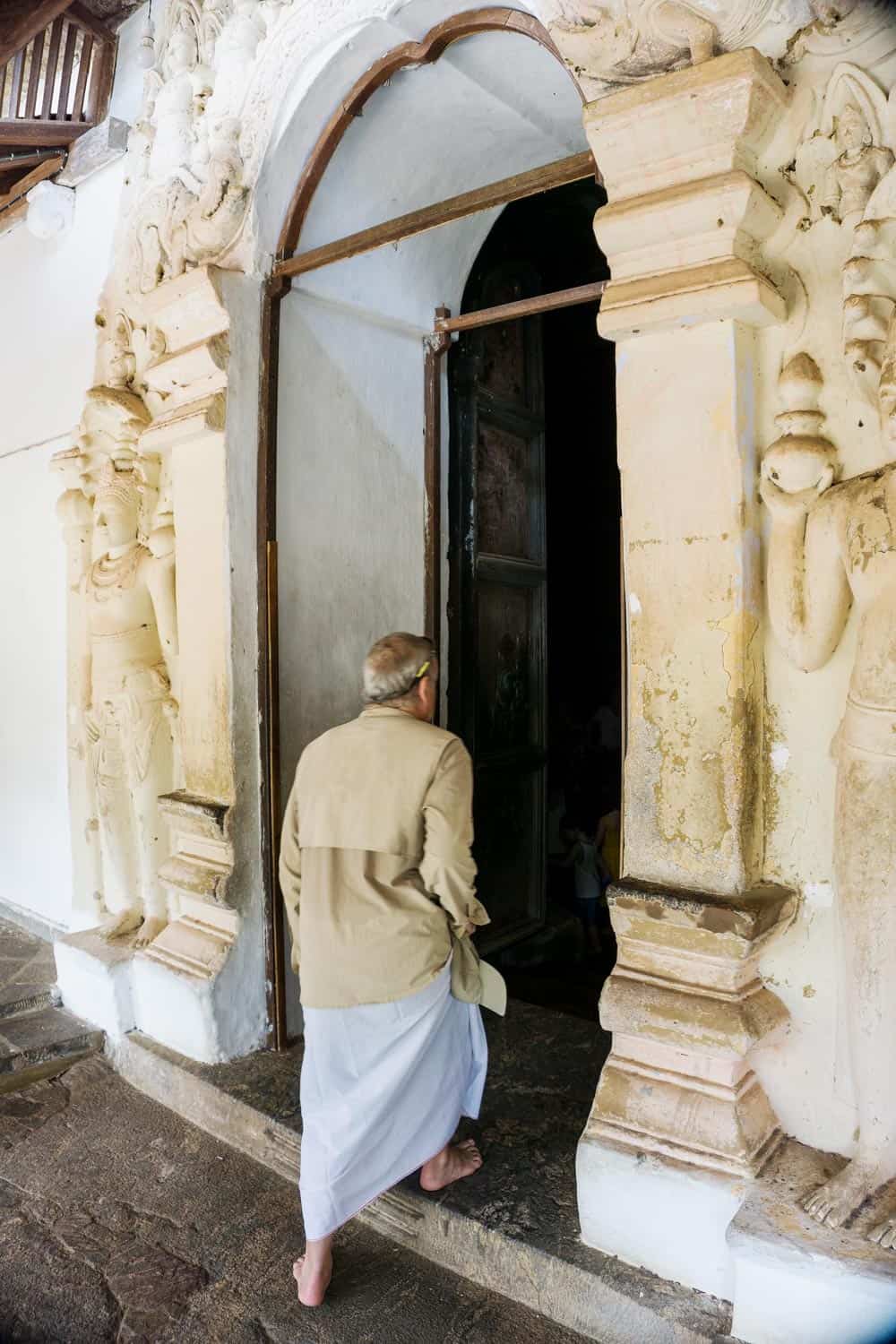 Man stepping inside temple cave in Dambulla