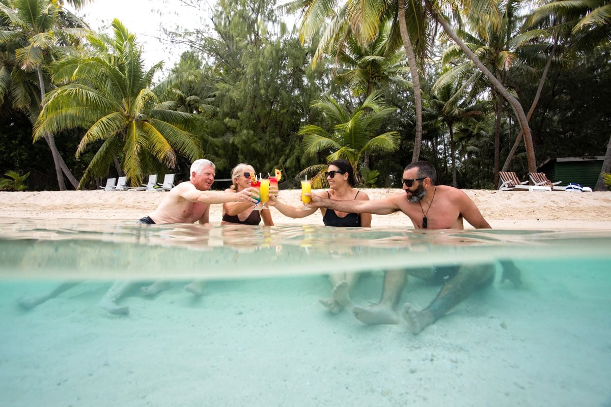 People sitting in the ocean by the beach drinking cocktails