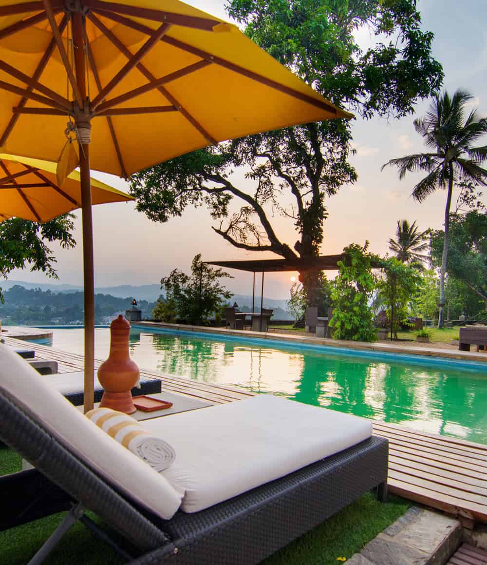 Yellow umbrellas overlooking a pool, with a pink sunset sky as the backdrop
