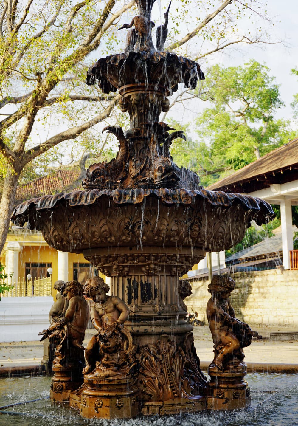 Ornate tiered fountain with sculpted figures and flowing water in Kandy, Sri Lanka