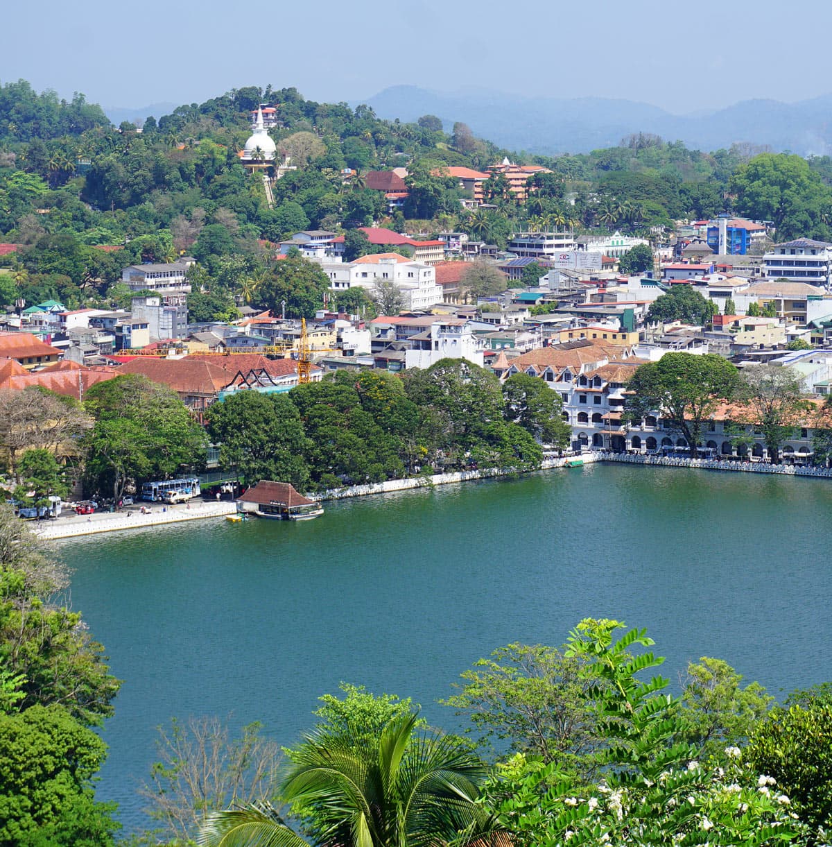 Panoramic view from the giant Buddha viewpoint over green Kandy Lake, the city’s rooftops and lush, forested hills