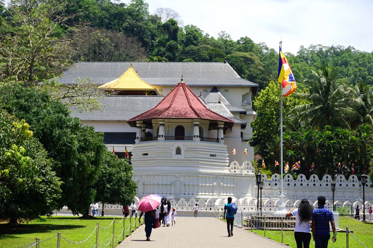 Visitors outside a white temple complex, with red and gold roofs
