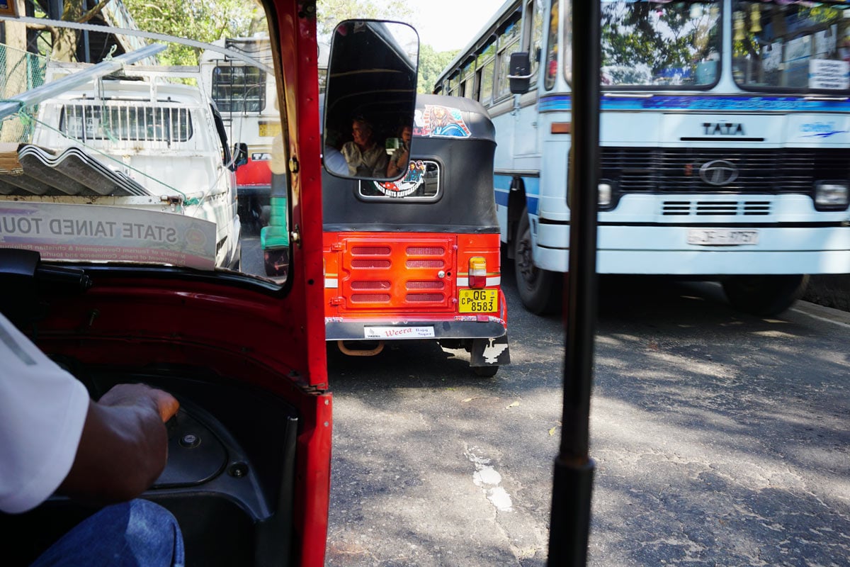 Inside a tuk-tuk on a busy Kandy road, with buses and another red tuk-tuk