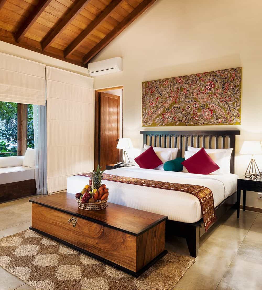 Guest room with soaring wood ceiling, red cushions on bed, and tile floors