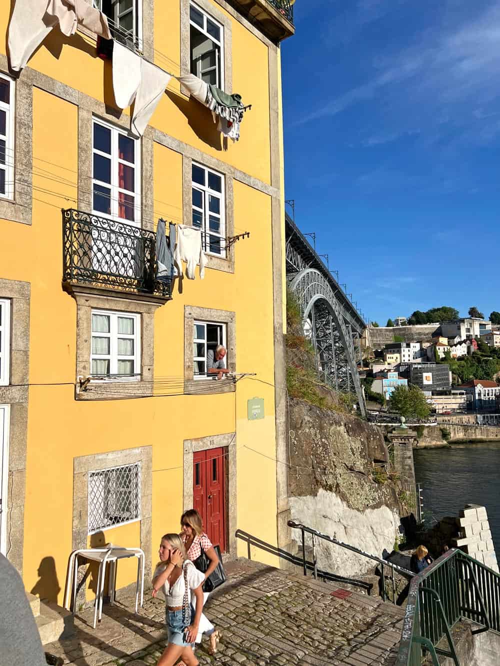Two women walk by gold yellow building in Porto