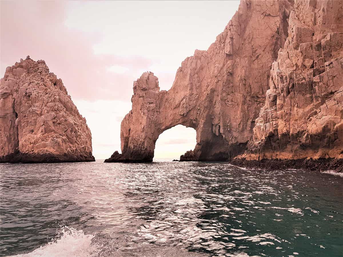 Cabo San Lucas Arch (El Arco) rising from the sea at Land's End, surrounded by towering golden-pink rock formations