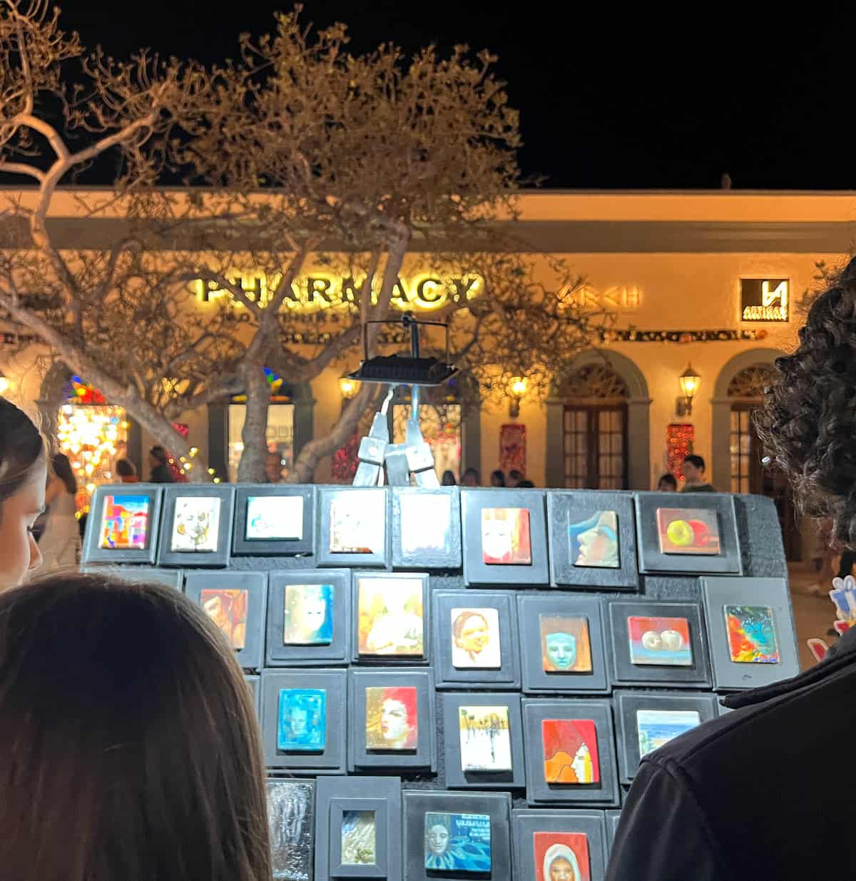 Visitors browse a display of small, colorful paintings during the evening Art Walk in San Jose del Cabo.