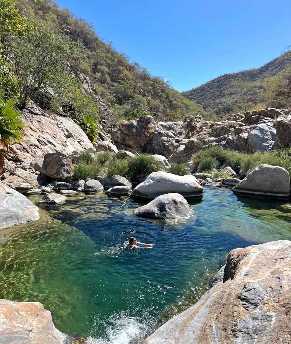 Woman swimming in a natural rock pool in the desert at Canyon of the Fox