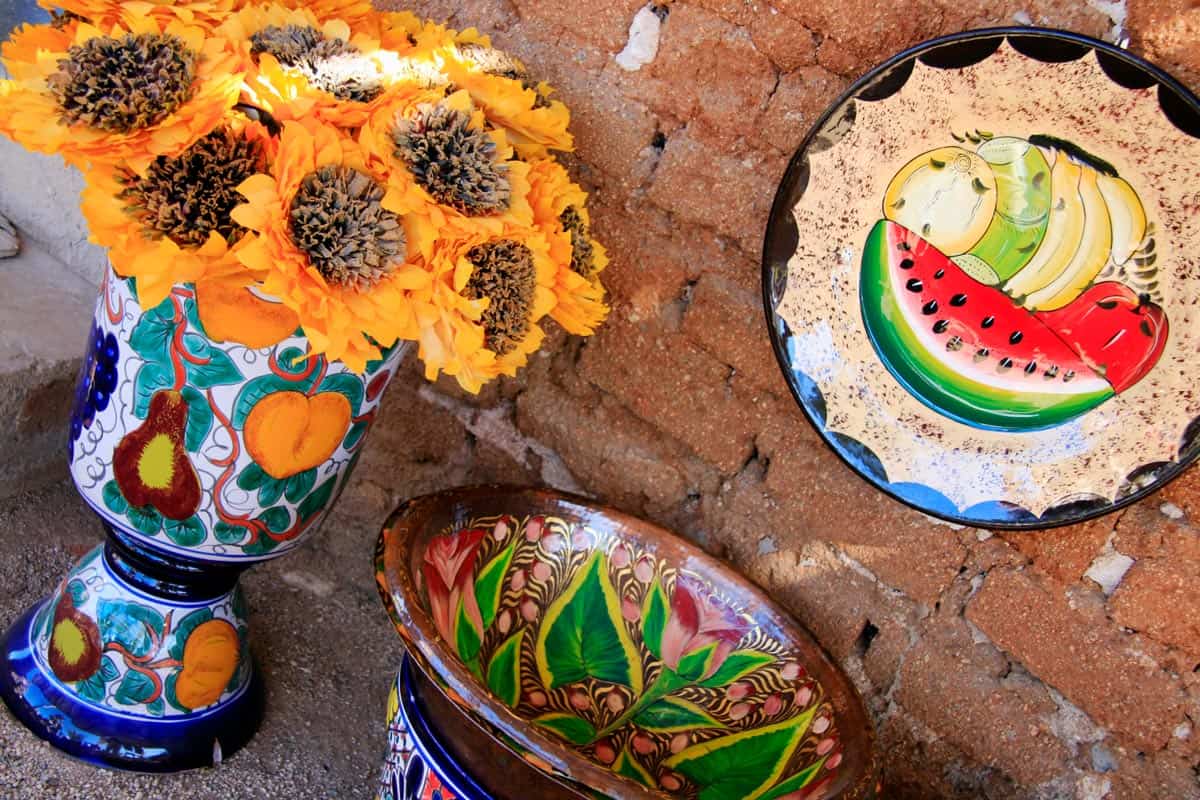 Colorful hand-painted Mexican pottery and bright yellow sunflowers on display in Todos Santos