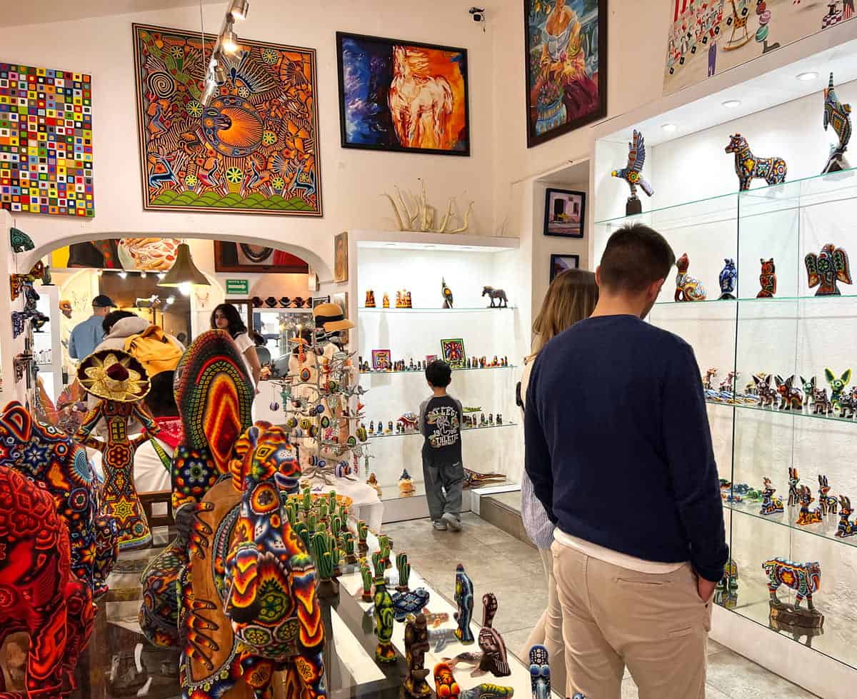 Visitors admire colorful Mexican folk art, beaded animal sculptures and paintings in a San Jose del Cabo art gallery.