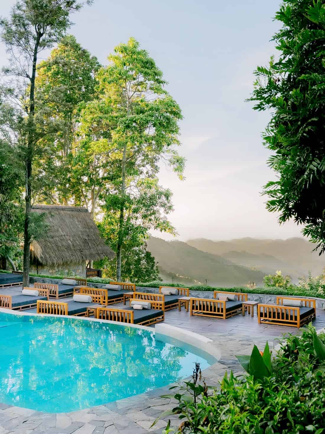 Swimming pool and double sun loungers overlooking the green mountains