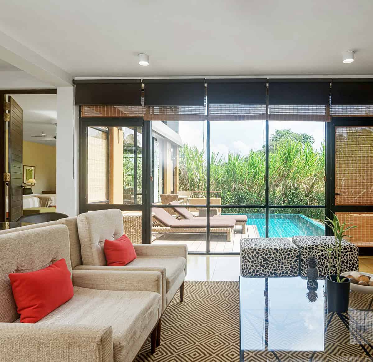 Beige chairs with red cushions in a living room overlooking private plunge pool