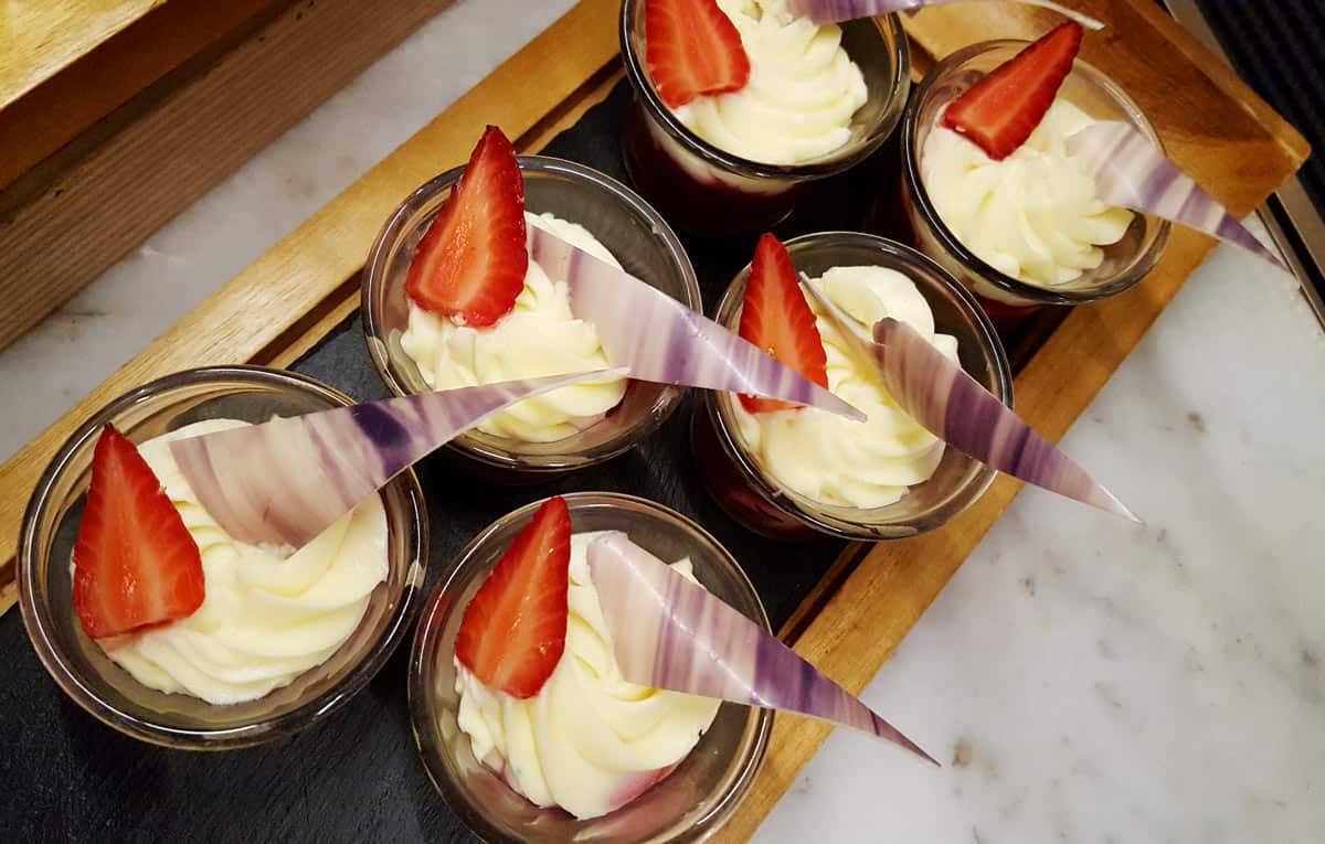 Little glass bowls of sweet custard with a slice of strawberry on top