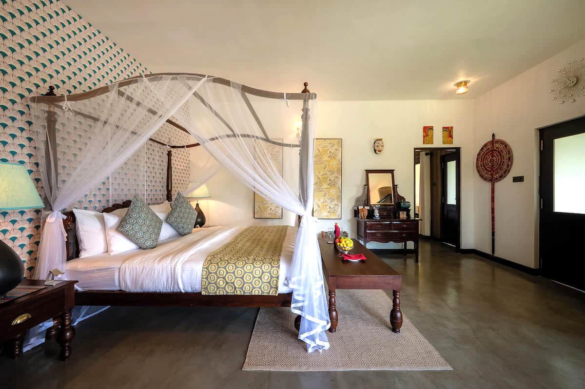 Bedroom at Riverdale Bungalow near Kandy, with a wood four-poster bed, antique furnishings and polished stone floors