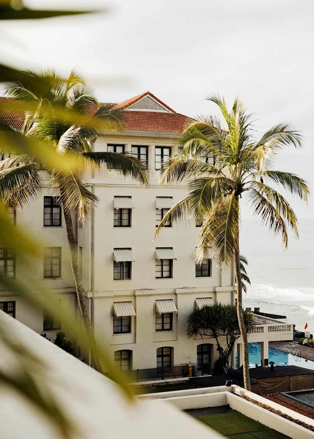 White exterior of Galle Face Hotel, framed by tall green palms