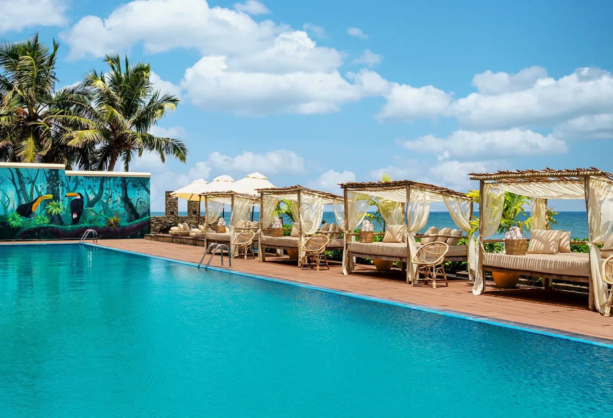 Turquoise oceanfront swimming pool with shaded cabanas at Galle Face Hotel in Colombo, Sri Lanka