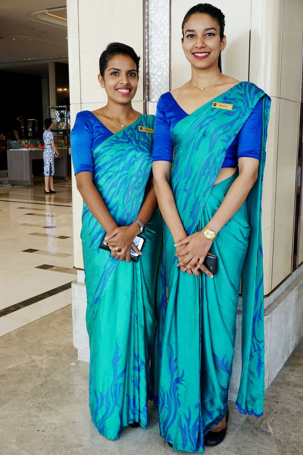 Two young women in emerald and turquoise saris stand at the entrance to the Shangri-La Colombo.