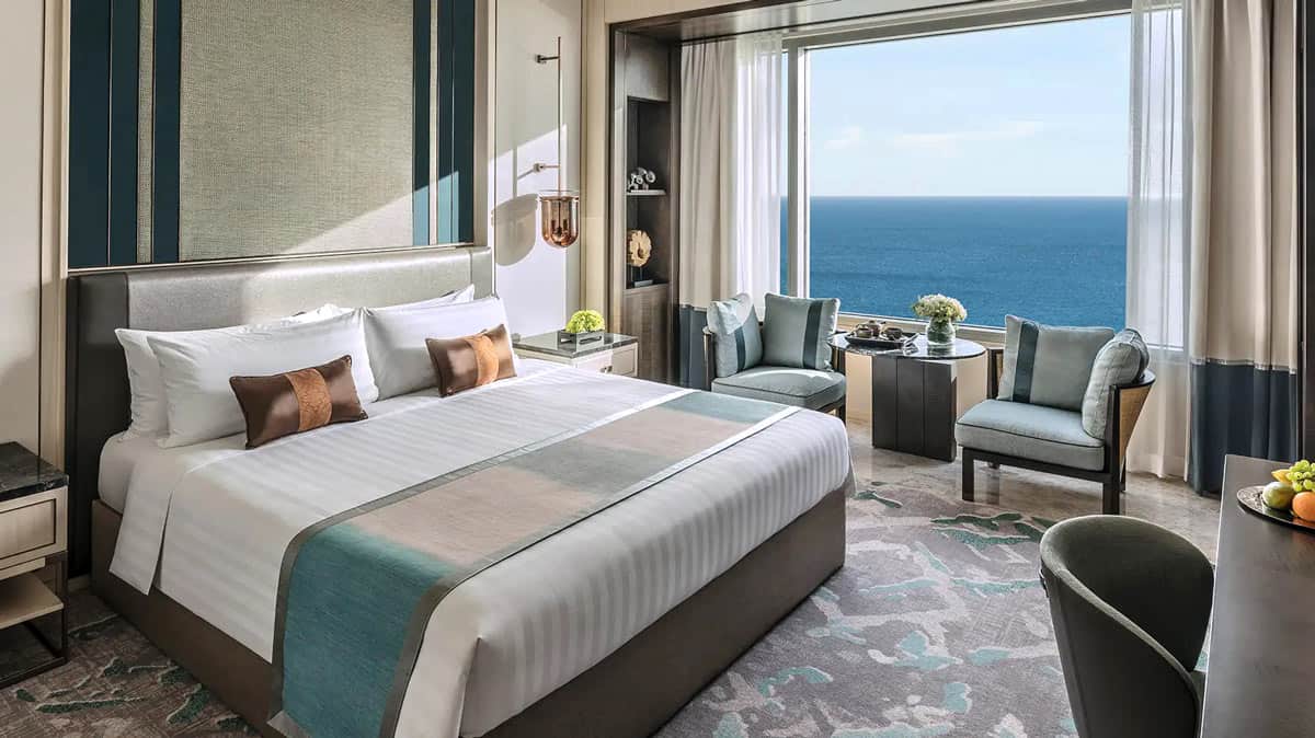 Shangri-La Colombo guest room with window with ocean view, bed with white linens and aqua furnishings