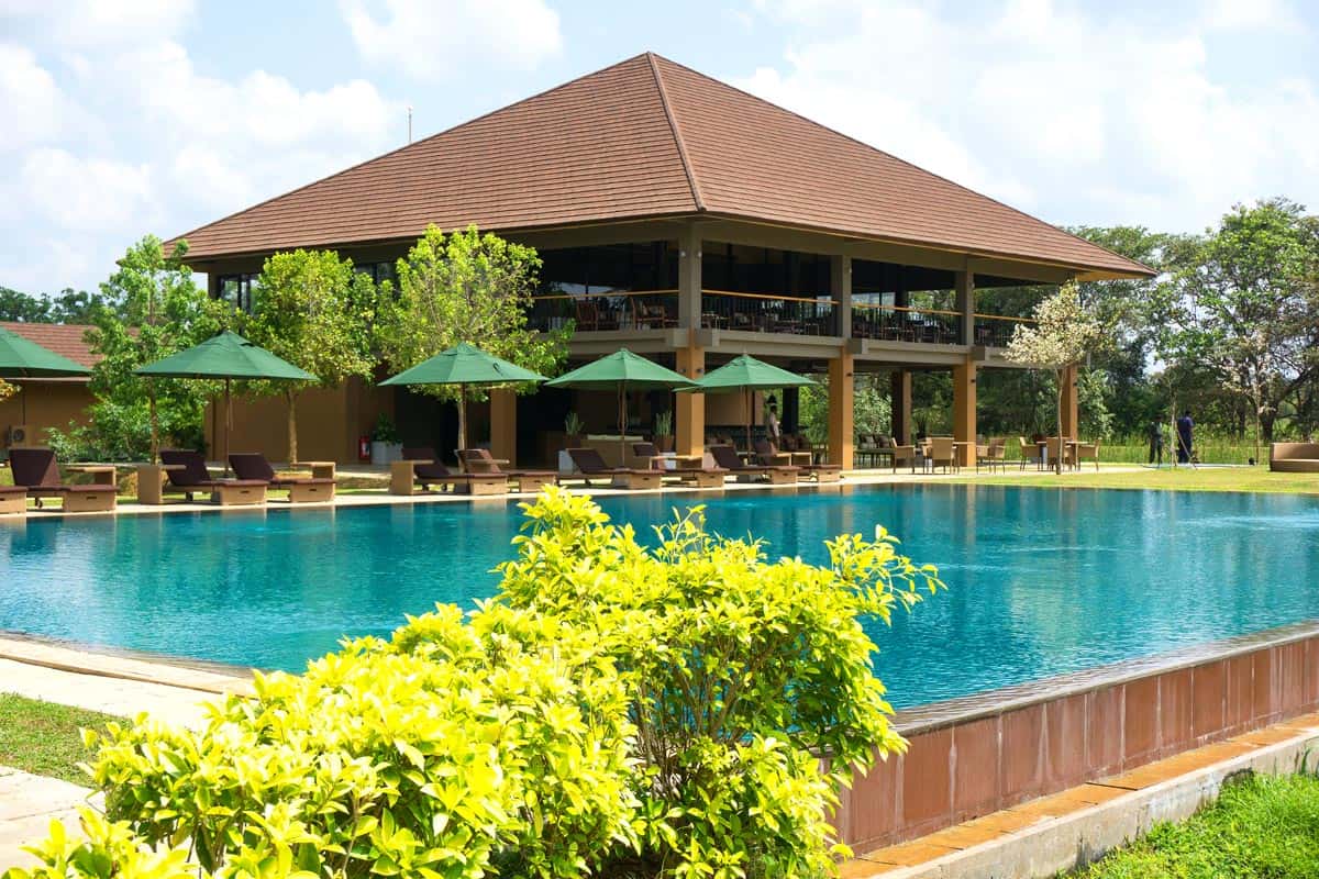 Swimming pool with loungers under green umbrellas at Water Garden Sigiriya, Sri Lanka