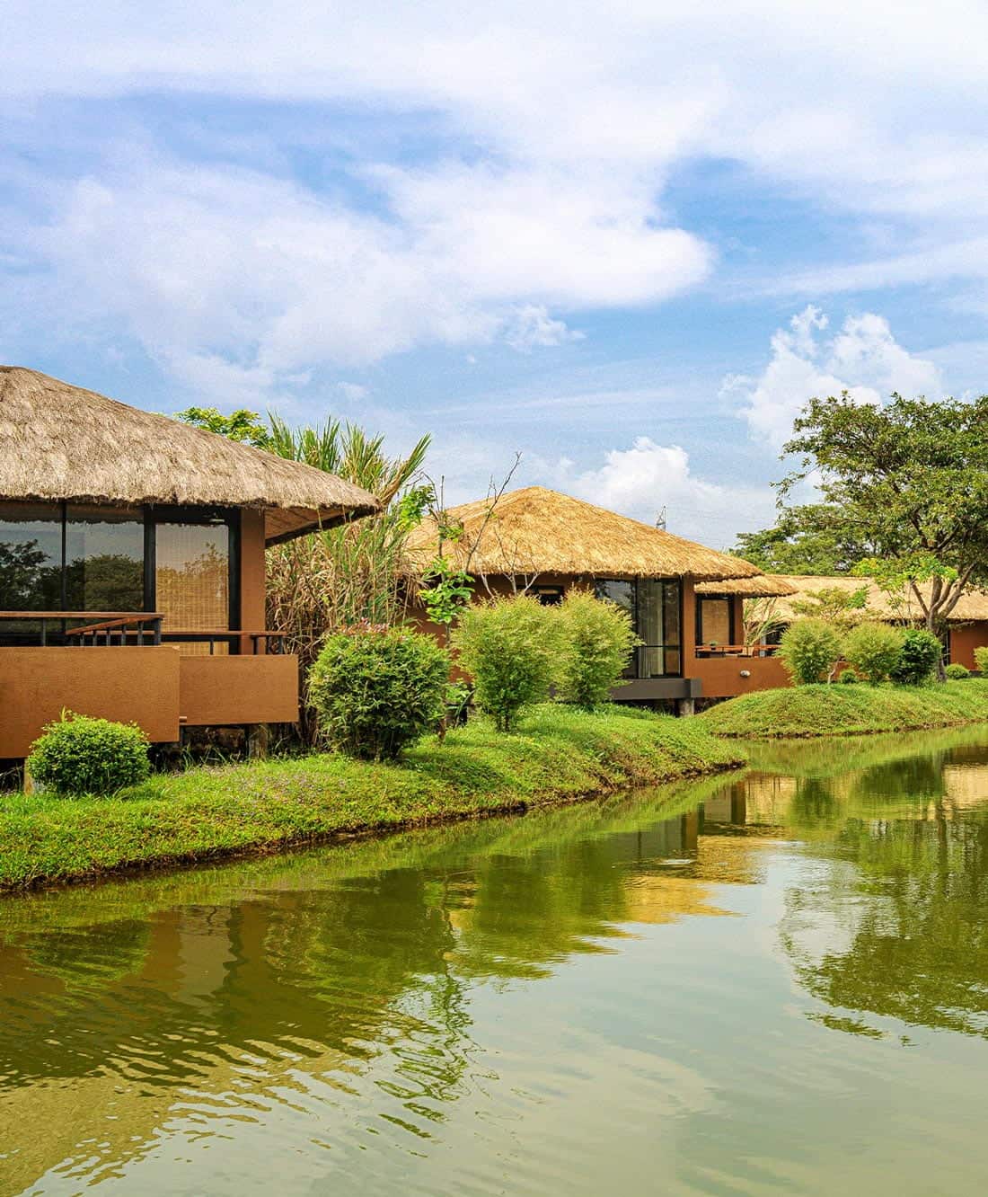 Brown wood, thatch-roof chalets along a waterway