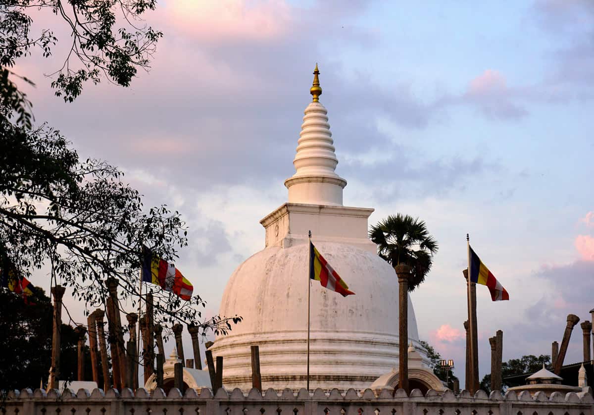Enormous white Buddhist stupa with colorful prayer flags in Anuradhapura, Sri Lanka