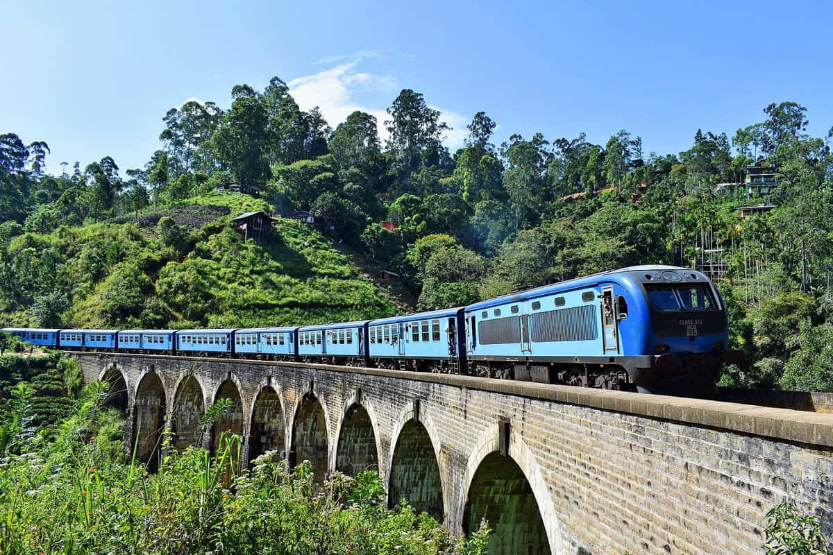 Blue train from Kandy to Ella rumbles over an arched bridge.