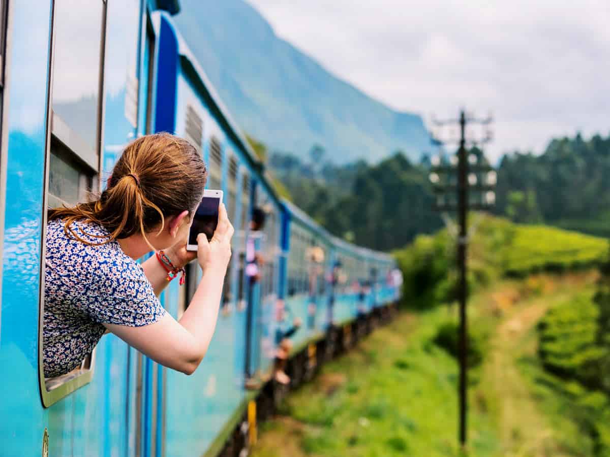Woman takes photos on her cell phone from the window of the blue Kandy-to-Ella train.