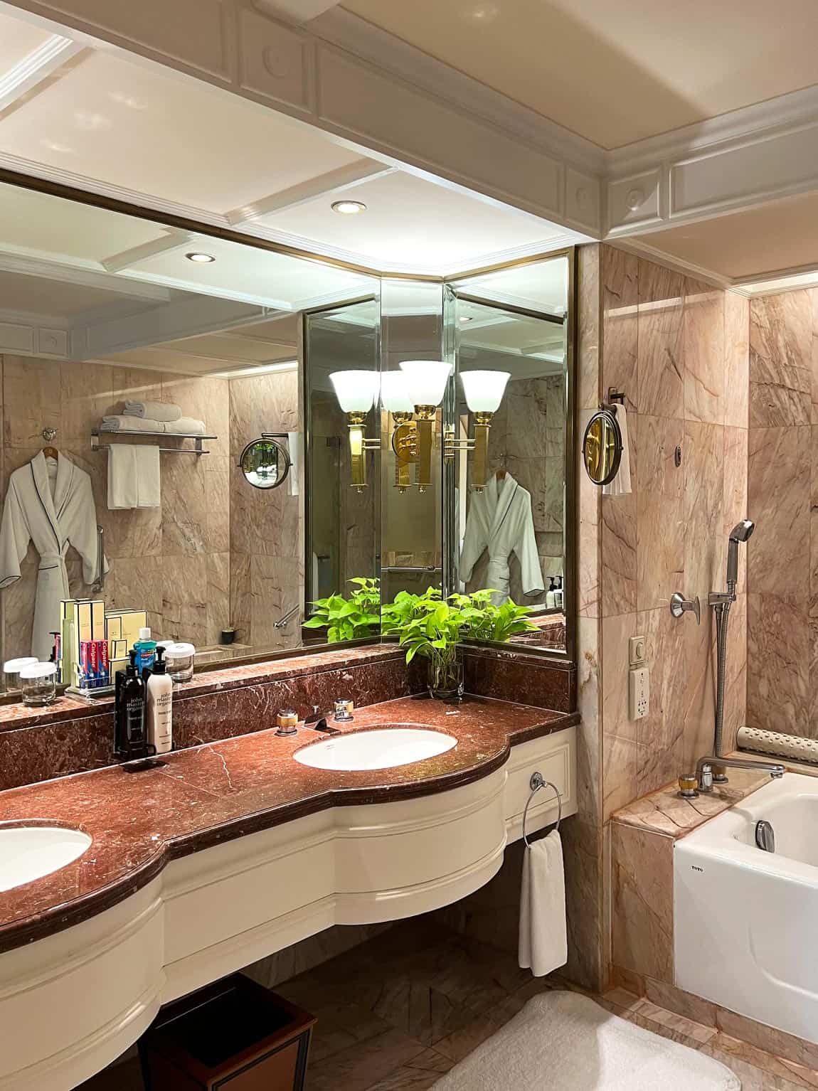 Spacious red-and-cream marble bathroom in a Krungthep Wing River View Room with a double vanity, large mirrors, bathtub and separate shower