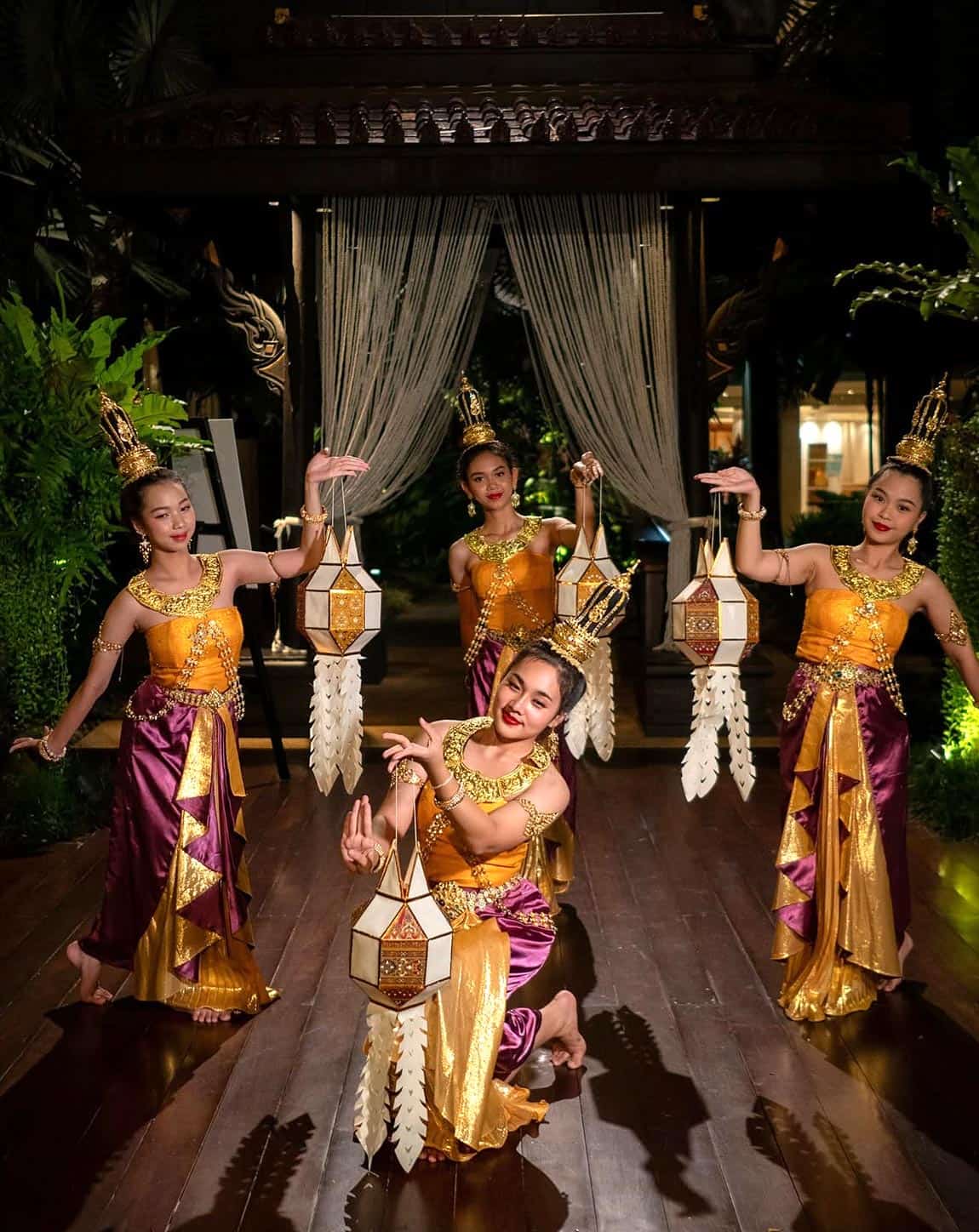 Traditional Thai dancers in colorful gold and purple costumes perform with decorative lanterns at Salathip restaurant.