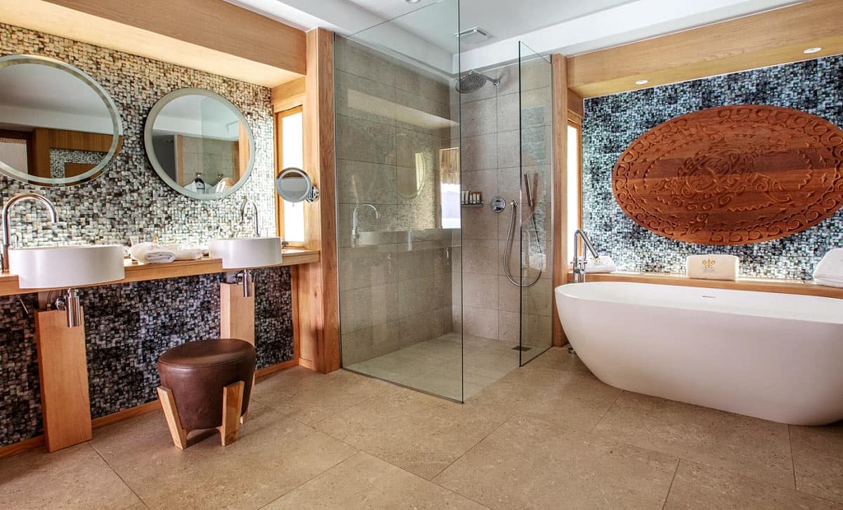 Bathroom of Le Bora Bora overwater bungalow with white stand-alone tub and round mirrors