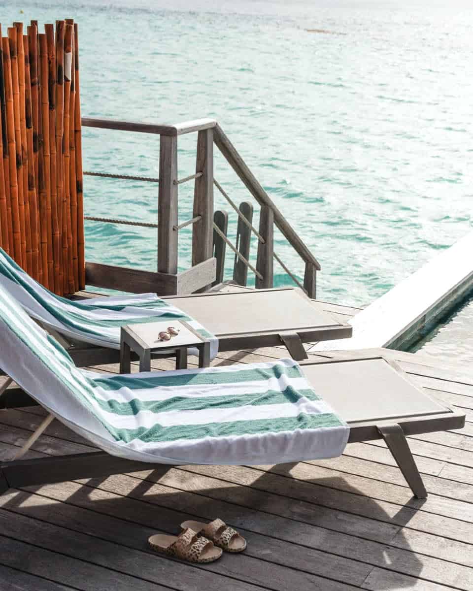 Two loungers with towels and sandals, on deck overlooking turquoise water