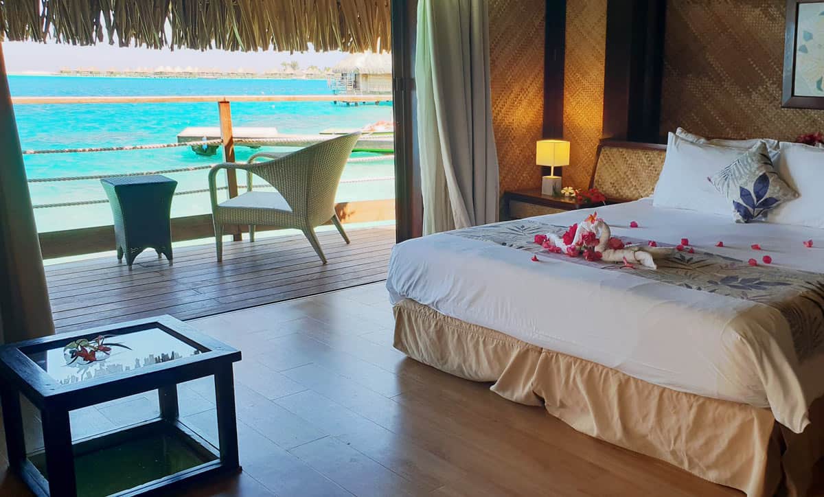 Bedroom with sliding glass doors to deck over the water at Matai Bora Bora