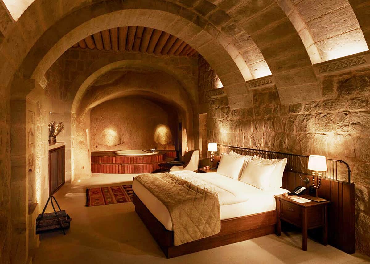 Cave suite with arched stone ceiling, king bed and jacuzzi tub