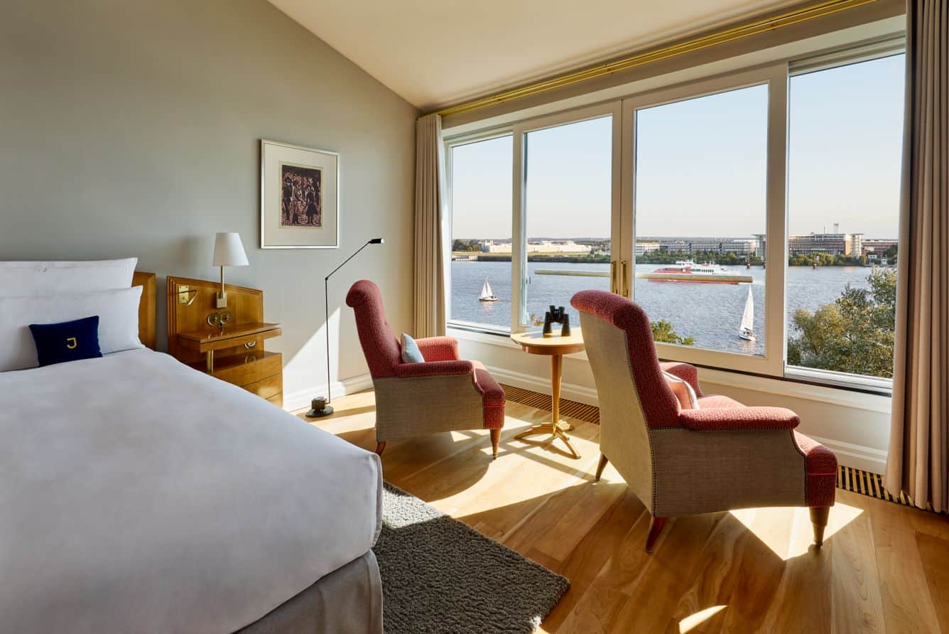 Deluxe guest room at Louis C. Jacob hotel, with two red arm chairs facing the Elbe River view