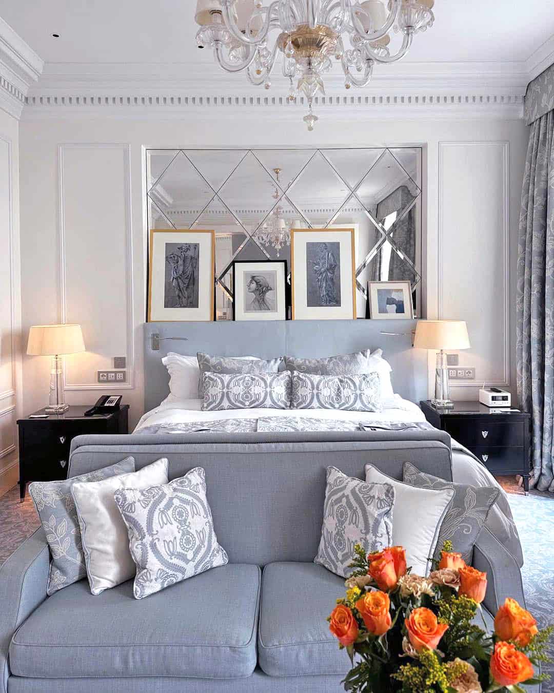 A room at The St. Regis Rome, with pale blue furnishings and a vase of orange flowers