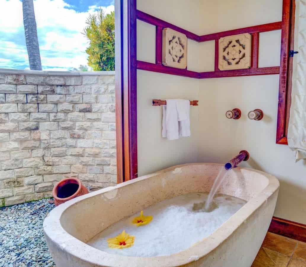 Ho'olio House's Kohala room has a bathroom with an ivory stone tub with a bamboo spout.