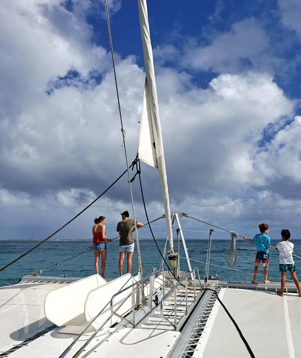 Couple and two children stand at bow of sailing boat