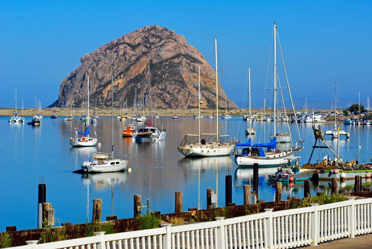 Morro Rock rises up behind boats in the harbor at Morro Bay, California