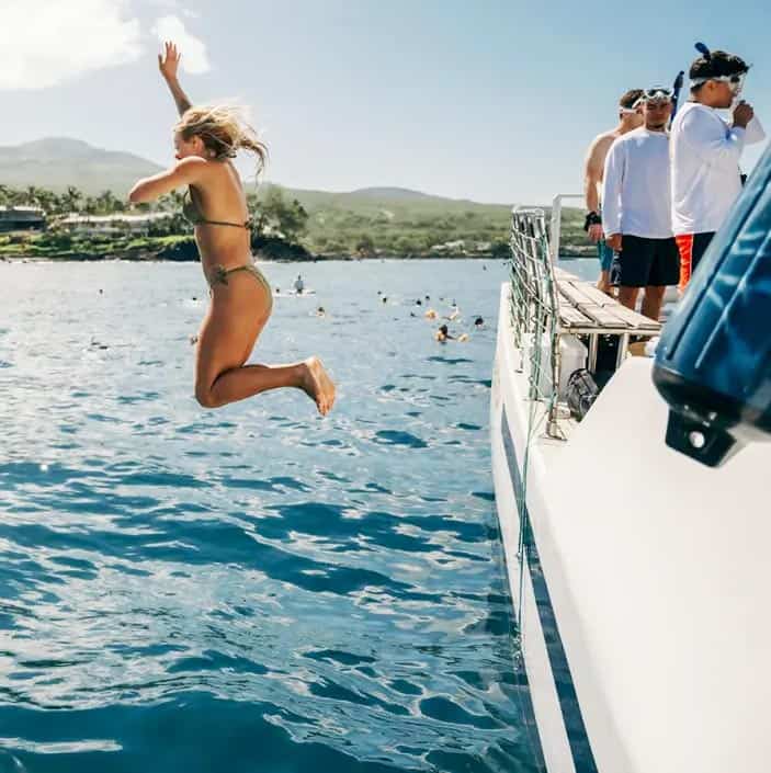 Young woman jumping off Malolo boat in Maui