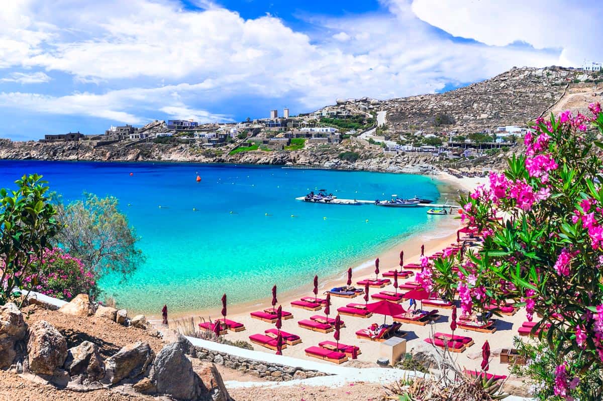 Beautiful Mykonos beach with pink beach chairs and umbrellas